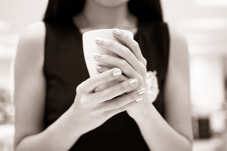 Cup in female hands black and white colourの写真素材