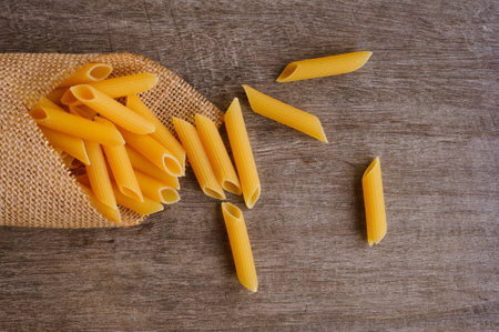 uncooked italian pasta penne on wood backgroundの写真素材