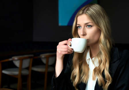 Atractive young woman drinking coffee in the morning at restaurant and thinking about new start-up project idea. Milenial lifestyle.の写真素材
