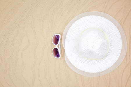 top view travel beach background concept with sunglasses and beach hat on sand.の写真素材