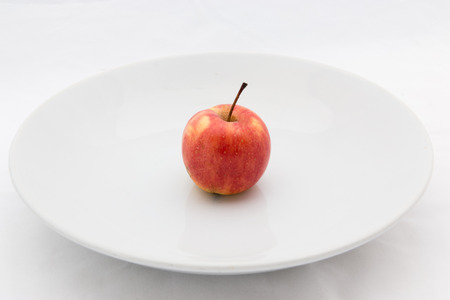Small white apple on the big plate.の写真素材