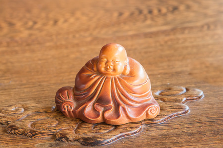 Chinese wooden Buddha statue sits on a small cloud.
