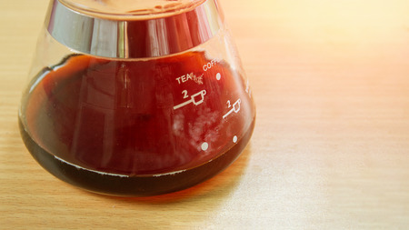 Close-up coffee glass jug on wood.