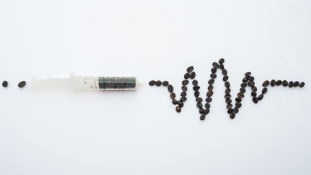 Heart wave shaped coffee beans and syringe concept on white background.の写真素材