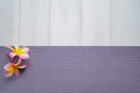 Plumeria flowers and purple yoga mat on a white wood floorの写真素材