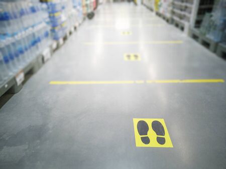 Yellow marker strips of a shopping centre, showing customers in the queue the correct distance to avoid infection with the Corona virusの写真素材