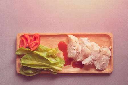 Top view of chicken boiled with vegetables served on wooden plate on  gray cloth backgroundの写真素材