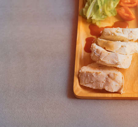 Top view of chicken boiled with vegetables served on wooden plate on  gray cloth backgroundの写真素材