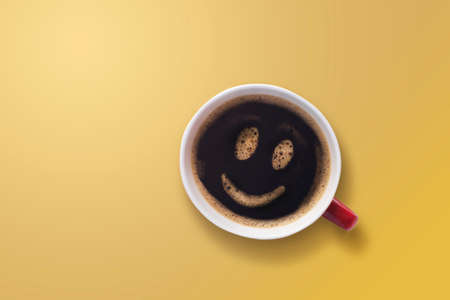 froth milk foam smiles in a cup of coffee on yellow background.の写真素材
