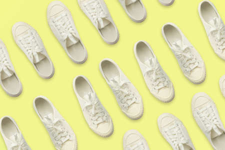 Pair of white sneakers on yellow background