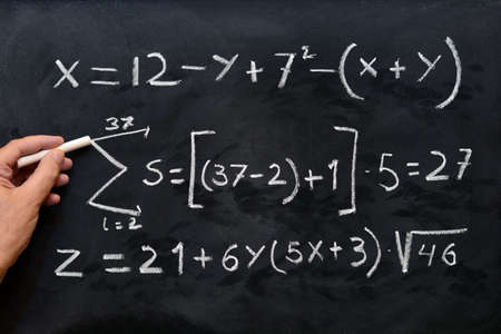 Mathematical equations handwritten with white chalk on the blackboard