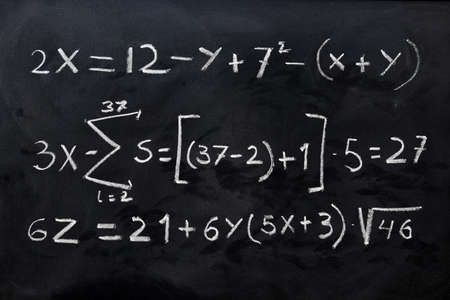 Mathematical equations handwritten with white chalk on the blackboard