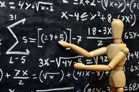 Wooden mannequin with background of a blackboard written with mathematical operationsの写真素材