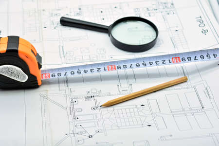 Pencil, ruler and magnifying glass on top of an architecture plan