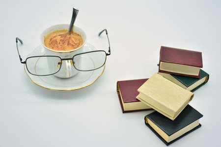 Cup of coffee with glasses, surrounded by books