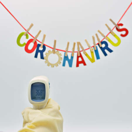 Digital thermometer marking 36.8 degrees and the word coronavirus made with colored letters out of...