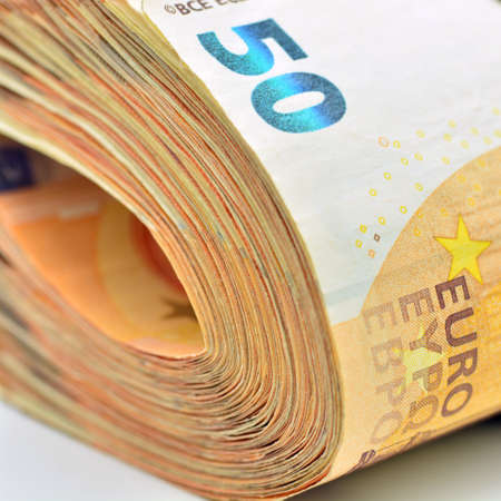 Detail of a bundle of money. 50 euro banknotes folded and tightened with band, isolated on white
