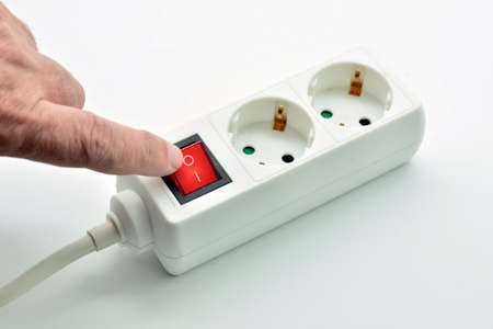 Finger turning off the power connector button to save electricity