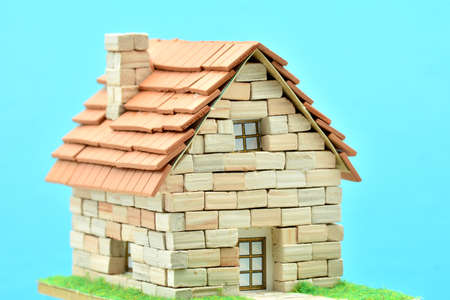 Handmade house with bricks and tiles, isolated on blue background