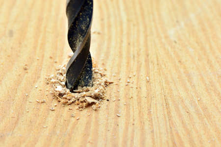 Detail of a drill opening a hole in a wooden board