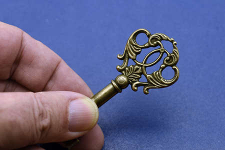 Hand holding an old key on blue backgroundの写真素材
