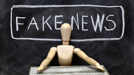 Articulated wooden doll sitting as a fake news presenter, fake newsの写真素材