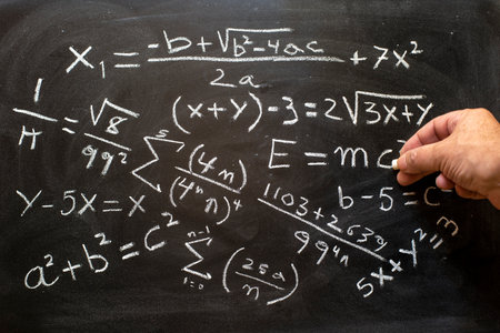 Hand writing math equations with a white chalk on the blackboardの写真素材
