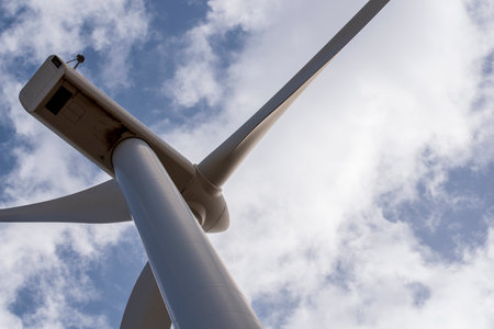 Detail of a wind turbine seen from below with the sky and clouds in the backgroundの写真素材
