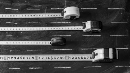 Flexometers spread on a blackboard with white chalk strokes as a road, in black and white
