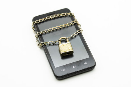 Mobile phone locked with chain and padlock, isolated on whiteの写真素材