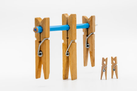 Wooden clothespins of different sizes with a blue pencilの写真素材