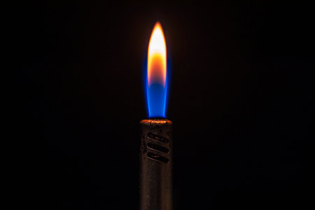 Detail of the lit flame of a blue gas lighter in the dark