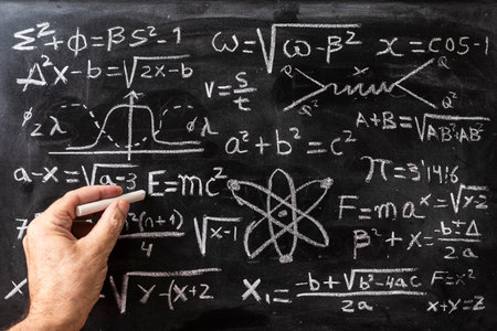 Hand writing mathematical operations and quantum physics formulas with a chalk on the blackboardの写真素材