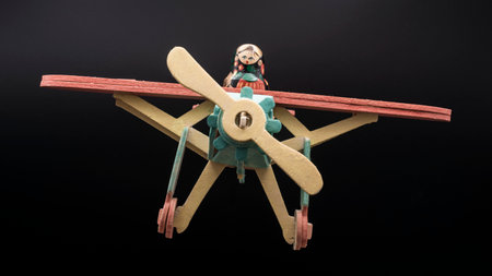 Matryoshka doll mounted on a colorful wooden airplane, isolated on black background