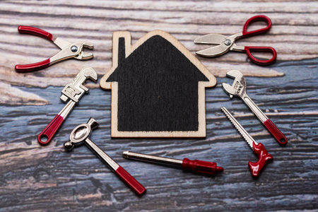 Silhouette of a wooden house surrounded by miniature construction toolsの写真素材