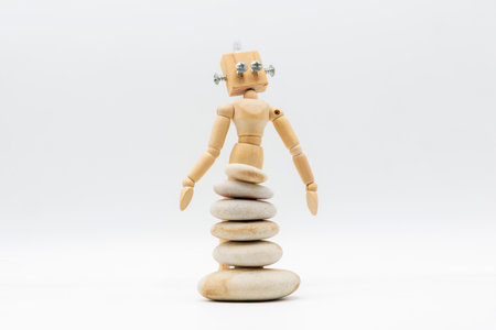 Wooden doll with a robot head, with stones stacked in front of it, resembling a surreal skirtの写真素材