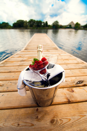 Bucket with champagne and berries on the pierの写真素材