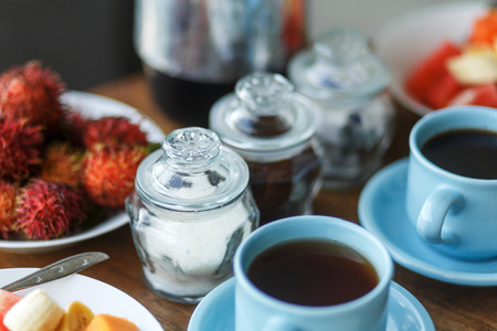 Traditional balinesse breakfast with two blue cups of hot drink on wooden table