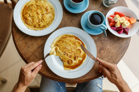 guy cuts banana pancakes breakfast in a hotel on baliの写真素材