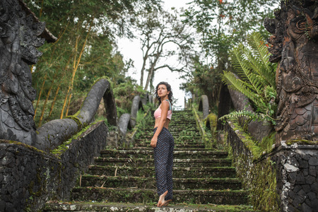 Young tourist girl looking in camera staying on old stone balinesse stairsの写真素材