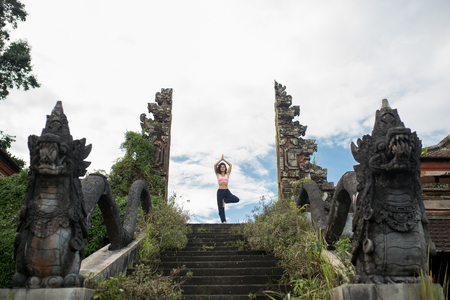 Woman staying in yoge pose at old stone stairs temple entrance balinesse gateの写真素材