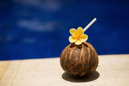 Coconut drink with yellow flower at poolside.