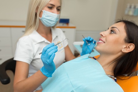 Pretty girl having mouth checkup in hospital by professional female dentist.