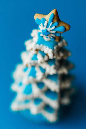 Blue chirstmas tree gingerbread cookie on blue background. Holidays food and decoration concept.の写真素材