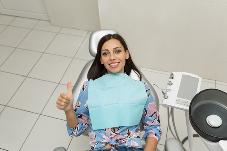 A young male dentist and happy female patient. Dentist office lifestyle scene. Doctor practice. Patient health care.の写真素材