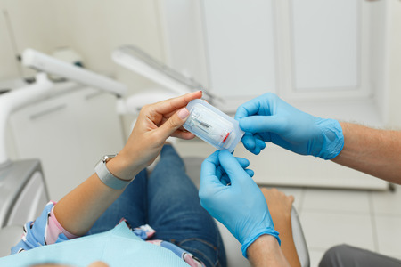 A young male dentist howing a sample of dentures to his patient. Dentist office lifestyle scene....