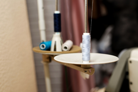 round plates of sewing machine with spools of threadsloaded into machine. Tailor industry concept.の写真素材