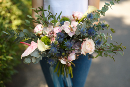Closeup woman florist decorator hold beautiful fresh flower bouquet for 
bride. Event decoration. Florist workflow. Wedding banquet design.の写真素材
