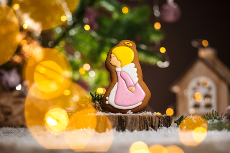 Holiday traditional food bakery. Gingerbread cute angel girl in cozy warm decoration with garland lights.の写真素材