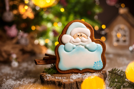 Holiday traditional food bakery. Gingerbread santa claus with copy space in cozy warm decoration with garland lights.の写真素材